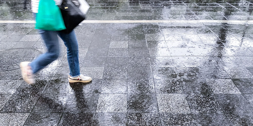 傘がさせず暴風雨の中歩く人